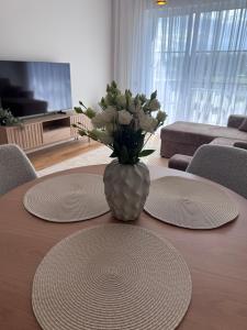 a table with two plates and a vase with flowers on it at Kukerpuu Kinnisvara in Raadi