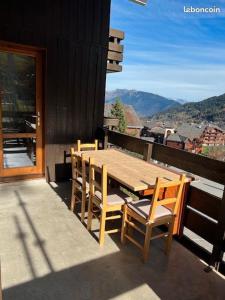 a wooden table and chairs on a balcony with a view at Chaletttt large and magnificent view in Valmorel