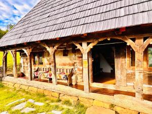 a log cabin with a porch and a dog standing outside at Hafia Legacy in Berbeşti