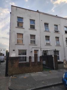 a white building with windows and a fence at Stadium Solution Flat in London