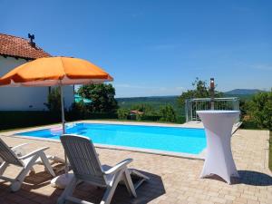 a pair of chairs and an umbrella next to a swimming pool at Villa Bavaria in Ritopek