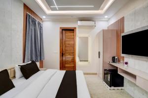 a hotel room with a bed and a flat screen tv at Hotel O Maruti Hotel in Indirapuram