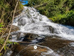a waterfall in the middle of a river at Refugio Marincek - Gonçalves - MG in Gonçalves