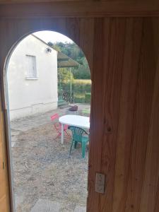 an open door to a patio with a table and chairs at Caravane au bord de la rivière in Saint-Corneille