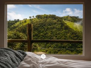 a view of a mountain through a window at Refugio Marincek - Gonçalves - MG in Gonçalves
