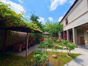 ein Garten mit Tischen und Stühlen und ein Steingebäude in der Unterkunft Christy Hotel in Goris