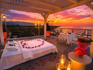 a bed on a deck with a sunset in the background at Panorama Suites & Spa - Adults Only in Stomio