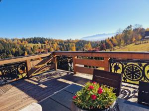 a wooden deck with a bench and flowers on it at Domek DeLuxe Spa z sauną i jacuzzi- Nowy Targ blisko Zakopanego i Białki Tatrzańskiej in Nowy Targ