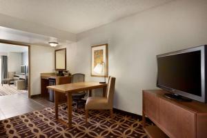 a hotel room with a desk and a flat screen tv at The Signature Suites in Irving