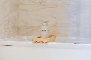 a white bath tub with a spray bottle on it at 2 Bed Flat, Pool Table, Terrace 4 stops to Wembley in Hatch End +38 photos