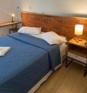 a bedroom with a blue bed and a brick wall at Requinte Hotel in São Paulo