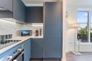a kitchen with blue cabinets and a window at 2 Bed Flat, Pool Table, Terrace 4 stops to Wembley in Hatch End