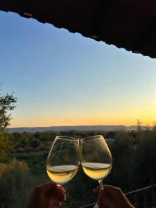 two glasses of white wine with the sunset in the background at Guest House Keli in Nënshat
