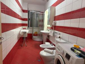 a red and white bathroom with two toilets and a sink at REA Apartment in Shkodër