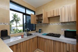 a kitchen with wooden cabinets and a sink and a window at Diani Luxe Villa 1bdr A, 600m from the beach in Galu