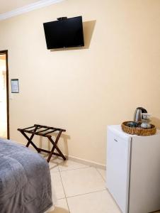 a room with a tv on a wall with a refrigerator at Aura de Cunha in Cunha