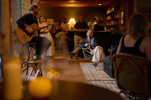 a group of people sitting in a living room playing guitar at The Alpine House in Jackson