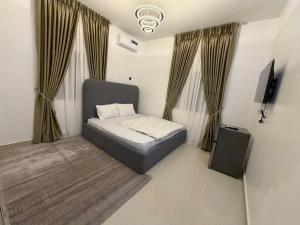 a small bedroom with a bed and a tv and curtains at Was Homes in Abuja +17 photos