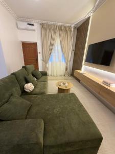 a living room with a green couch and a flat screen tv at Was Homes in Abuja