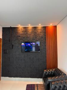 a living room with a couch and a tv on a wall at O mais charmoso do centro in Sinop
