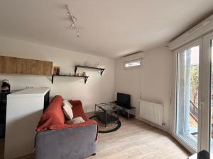 a living room with a couch and a television at Cocon avec petit jardin centre Bondy in Bondy
