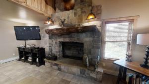 a living room with a stone fireplace with a television at Antlers Riverside Lodge in Red River
