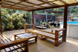 a patio with a table and benches and a pool at Spacious Family House with Pool in Afareaitu