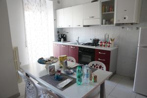 cocina con mesa, sillas y nevera blanca en La Casa dei Sogni, en Matera