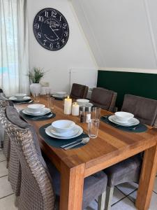 a wooden table with chairs and a clock on the wall at Caseo Gramsbergen in Gramsbergen