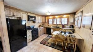 a kitchen with a black refrigerator and a table with chairs at Knotty & Nice in Red River