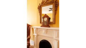 a mirror over a fireplace with a clock on it at Pancho Griego in Cimarron
