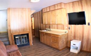 a kitchen with wooden cabinets and a tv on the wall at A Frame of Mind in Red River
