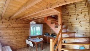 a wooden cabin with a table and stairs in it at Sosnowe Domki in Sarbinowo