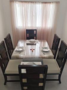 a dining room table and chairs with a glass table and chairsktop at Rinconcito Caribeno Apartment in San Pedro de Macorís