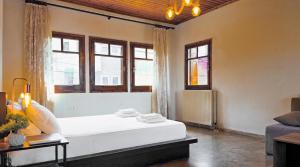 a bedroom with a large white bed and windows at Villa Hill in Tríkala