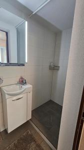 a white bathroom with a sink and a mirror at Haus Alpenhof in Wassen
