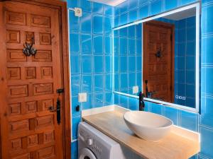 a blue tiled bathroom with a sink and a mirror at Formenterasuite 16 in Es Pujols +15 photos