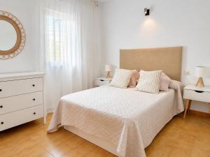 a white bedroom with a bed and a mirror at Formenterasuite 16 in Es Pujols
