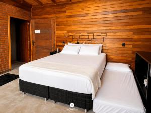 a bedroom with two white beds and a wooden wall at Cabana Bad Wolf - Rancho Queimado - SC in Rancho Queimado