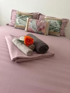 a bed with towels and a rose on it at The cozy escape in Satu Bucovei