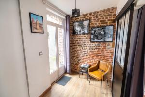 a hallway with a chair and a brick wall at Gîte la Maison Rouge Béthune in Béthune