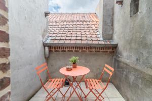 a table and chairs on a balcony with a roof at Gîte la Maison Rouge Béthune in Béthune
