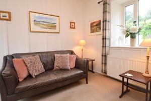 a living room with a leather couch and a window at Darroch Beag in Saint Catherines