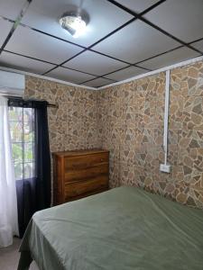 a bedroom with a green bed and a wooden dresser at La casa de Juana in Las Tablas
