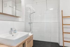 a white bathroom with a sink and a shower at Ferienwohnung Urlaubsglück- lichtdurchflutete Wohnung mit Balkon und Seesicht in Lindau