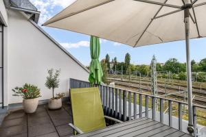 a balcony with an umbrella and a table and chairs at Ferienwohnung Urlaubsglück- lichtdurchflutete Wohnung mit Balkon und Seesicht in Lindau