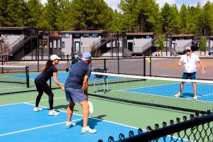 a group of people playing tennis on a tennis court at Village Camp Flagstaff in Bellemont