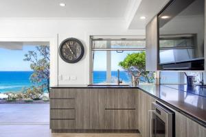 a kitchen with a large clock on the wall at Ocean Panorama With Private Pool! in Noosa Heads