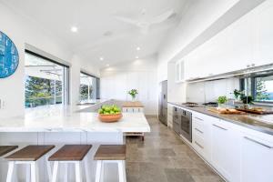 a large white kitchen with a counter and stools at Ocean Panorama With Private Pool! in Noosa Heads