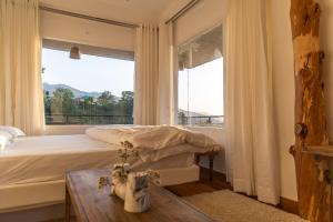 a bedroom with a bed and a large window at THHPSOCIETY - Exstacy stays & cafe - Your Romantic & Cozy Getaway - Mountain view , Hot tub , Parking - MUKTESHWAR in Mukteshwar